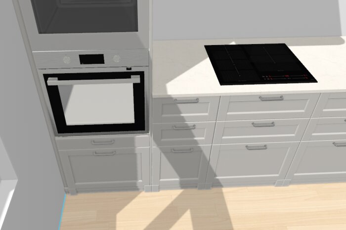 Inbyggnadsugn bredvid bänkskiva med induktionshäll ovanför gråa köksskåp. Sammanfogning av högskåp och bänkskiva syns tydligt.