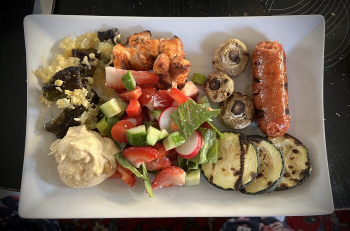 Grillad tallrik med chorizo, kycklingspett, svamp, grillad zucchini, sallad med gurka och paprika, hummus och gratinerad aubergine.