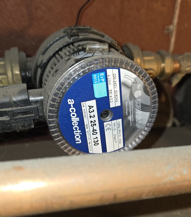 Cirkulationspump av märket Lowara, modell A3 25-40 130, installerad i ett hem för att reglera inomhustemperaturen, inramad av rör och ventiler.