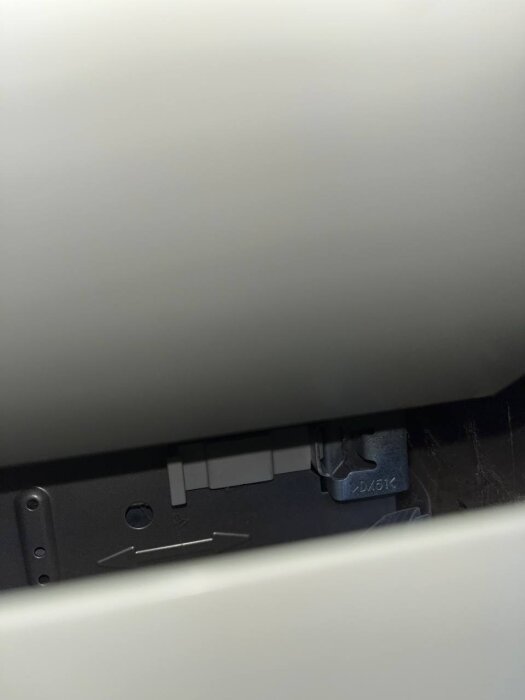 Närbild av ett diskmaskinsfäste och justeringsmekanism inuti ett köksskåp med synliga nummer och symboler på metallen.