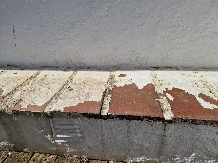 Flagnande färg på röda Höganäspannor på ventilerad klack, med avskavd puts och träytor, vid ett 1700-tals hus.