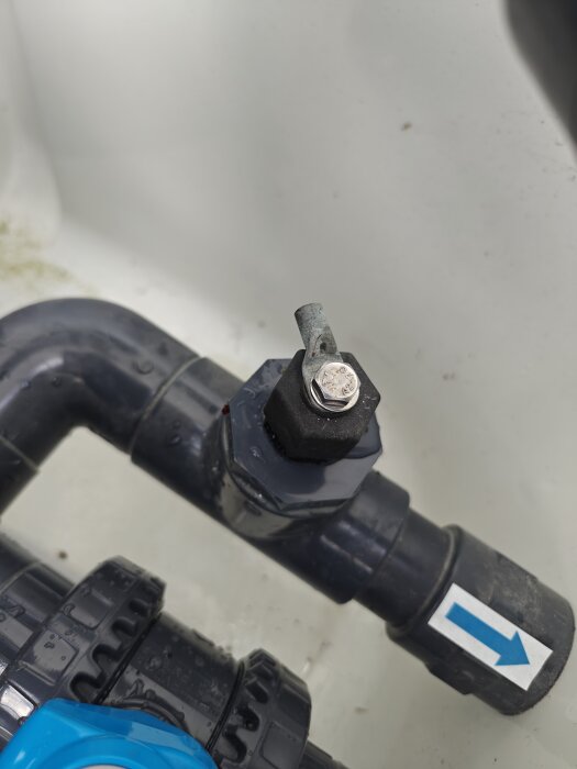 Ventil vid inloppet till värmepump, eventuellt läckande, med blå pilmarkering på röret.