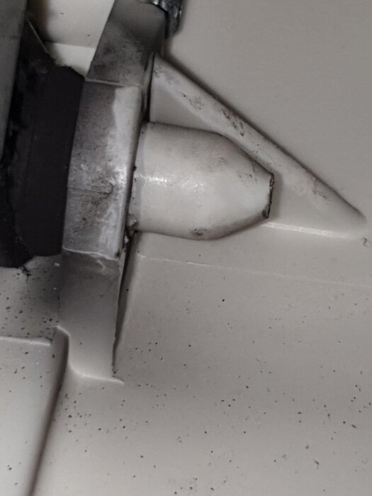 Närbild på en plastplugg som sitter fast i en Siemens-maskin, del av en dämpare.