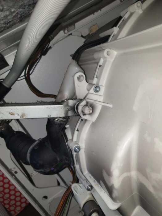 Inre mekanismen av en Siemens tvättmaskin med fokus på dämpare och plastplugg som är svår att ta bort, omgiven av sladdar och skruvar.