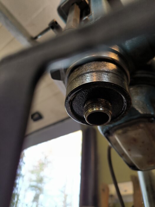 Närbild på en metallmutter på en pelarborrmaskin, med trådad kona tydligt synlig i mekanismen.