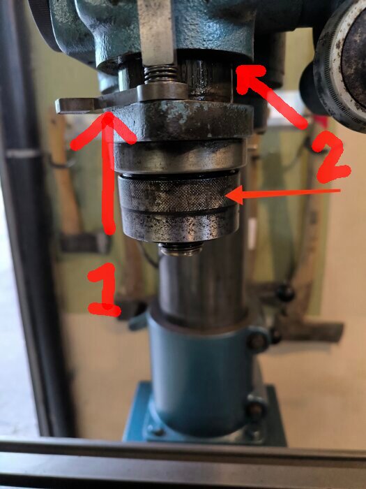 Bild på övre halva av chuck med två röda pilar markerade som 1 och 2; visar detaljer för att flytta eller justera spindeln.