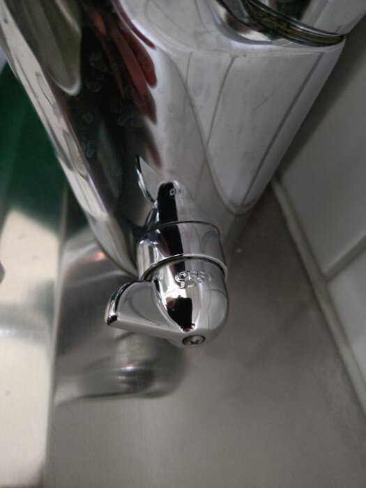 Manuell avstängningsventil i krom monterad ovanpå en diskbänk, del av ett diskussionsforum om diskmaskinsinstallation och vattenproblem.