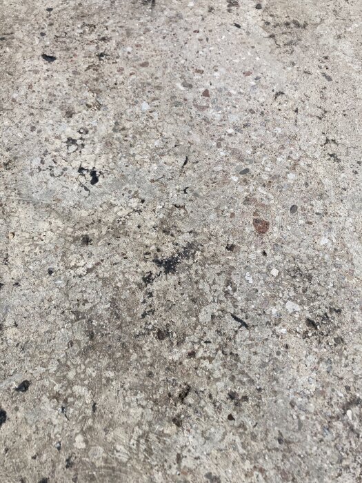 Grovslipad betongyta med fläckar och ojämnheter, från balkong under renovering. Sikt avlägsnat asfaltklister. Tänkbar terazzo-finish.