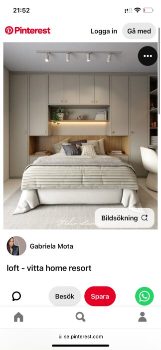 Sovrum med säng omgiven av garderober, inbyggd hylla med växt och böcker, gråa skåp och belysning ovan sängen.