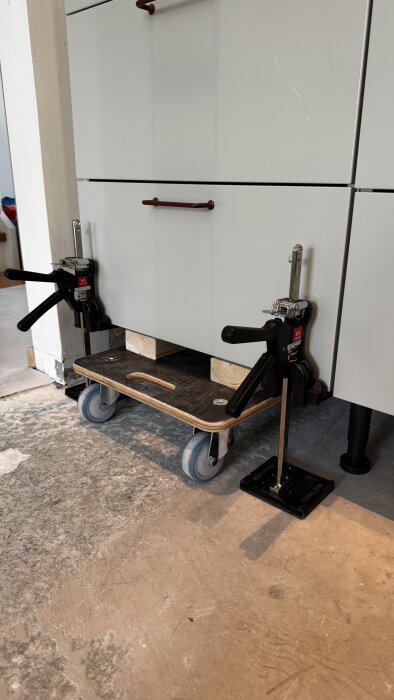 Bänkskåp monteras med hjälp av två Viking Arms och en rullvagn med fastsatta reglar för justering, allt på ett betonggolv.