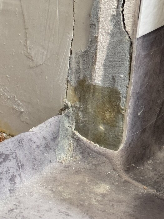 Våtrumsmatta vid dörrkarm med silikon över skurna hörn, matta vikt upp längs väggen, visar potentiellt fel vid tröskelinstallation i badrum.