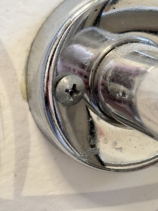 Närbild av en handdukstork monterad med olika skruvar. Bilden visar en kromad del med en skruv med stjärnformad skåra.