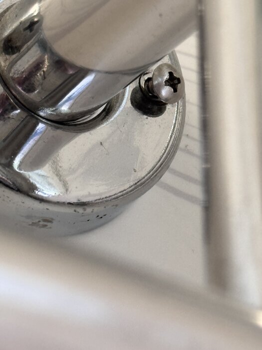 Handdukstork monterad med olika skruvar, visar en skruv ovanpå en rund, metallisk infästning.