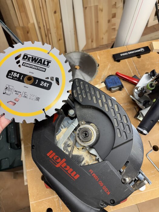 En cirkelsåg med en ny Dewalt-klinga förbereds för snickeriarbete, omgiven av verktyg och trämaterial på arbetsbänken.
