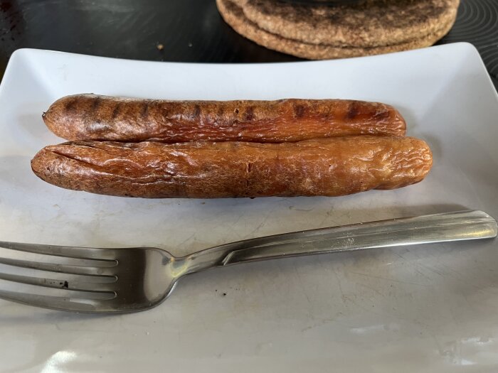 Grillade korvar på en tallrik med en gaffel, redo för Valborgsmässoafton.