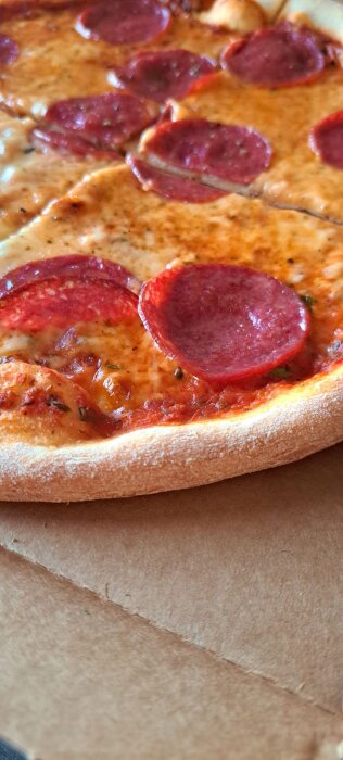 Pizza med pepperoniskivor på kartong.