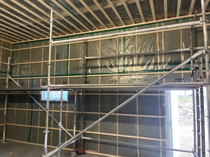 Väggar och tak med isolering och plast samt byggställning inomhus.