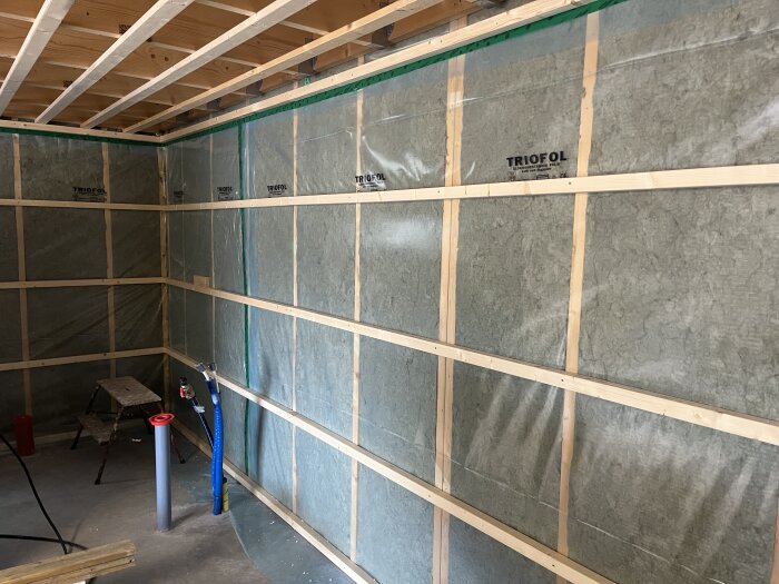 Isolerade väggar med plastfolie och 2”2-reglar, pågående eldragning i ett rum under renovering.