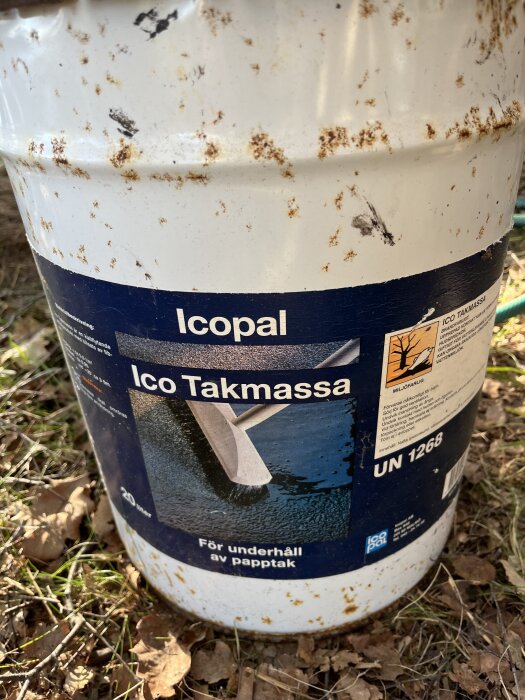 Gammal hink med Icopal Ico Takmassa stående på mark, etikett anger användning för underhåll av papptak.