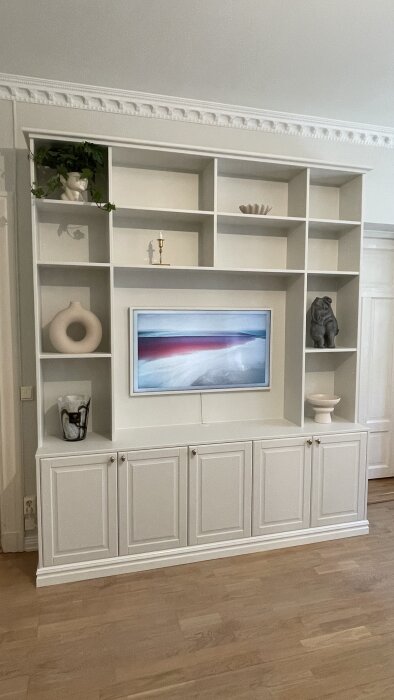 Platsbyggd bokhylla med inbyggd TV och dekorativa föremål, skapad med IKEA Metod-skåp och anpassade täcksidor för ett snyggt utseende.