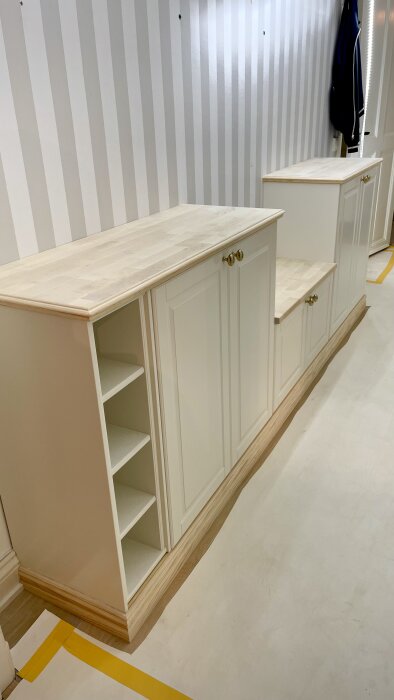 Vita inbyggda skåp från IKEA Metod med täcksidor och MDF som skapar ett platsbyggt utseende, placerade mot en randig vägg.