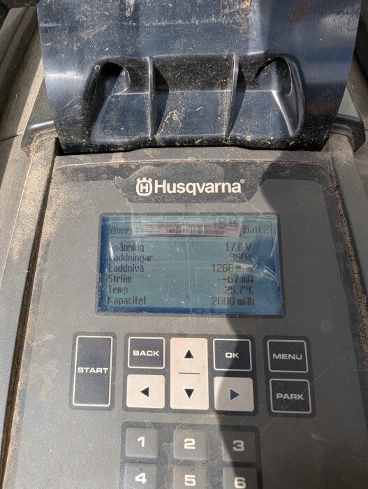 Display på Husqvarna gräsklippare visar laddningsinformation: spänning, antal laddningar, laddnivå, ström, temperatur och batterikapacitet.