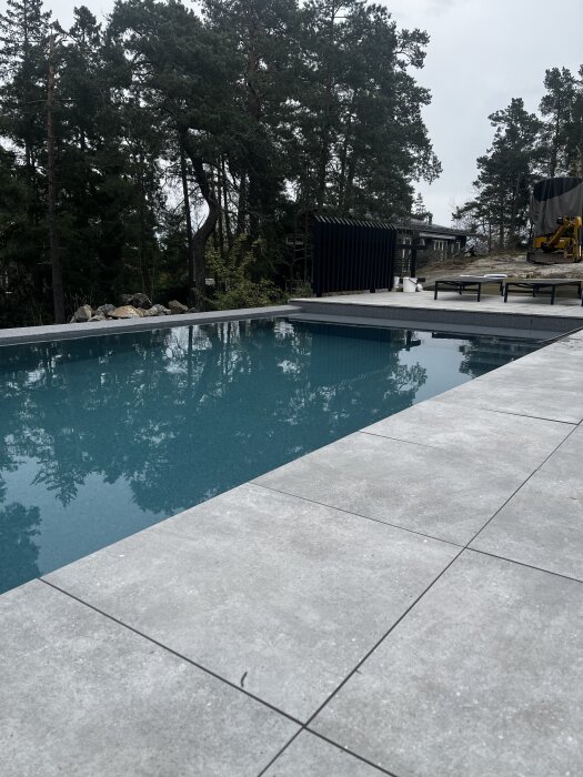 Utepool med klart blått vatten och omgivande träd i bakgrunden.