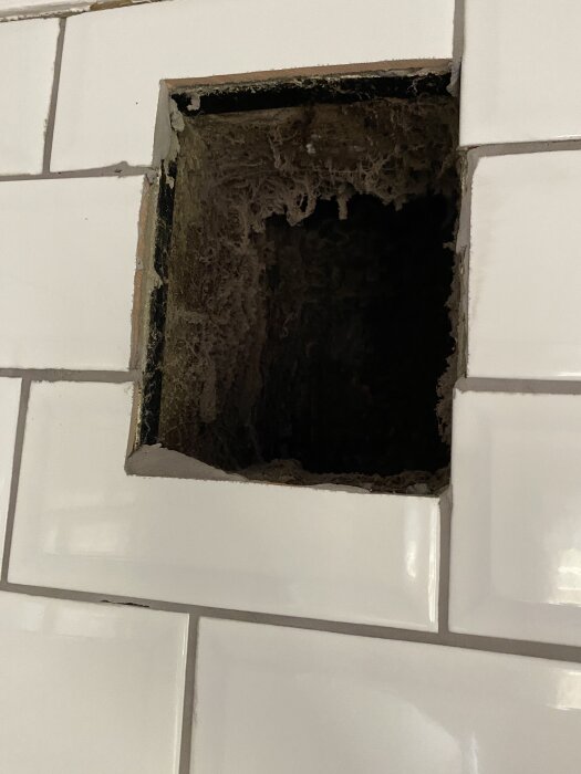 Öppning i kakelvägg för imkanal där köksfläkt ska anslutas; ingen spirorör installerat.