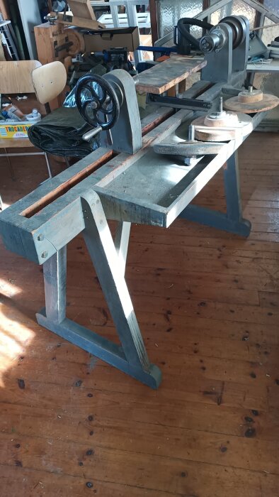 Gammal snickeriverkstad med verktyg som såg, hyvel, svarv och fräsbord på ett träbord i ett verkstadsutrymme.