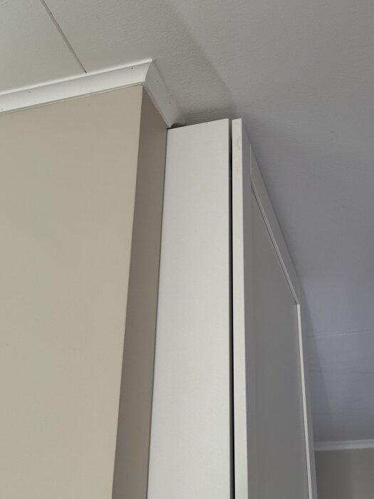 Väggdel som avslutas intill en vit hallmöbel med litet mellanrum, visar behov av förlängning för att ge inbyggd look.