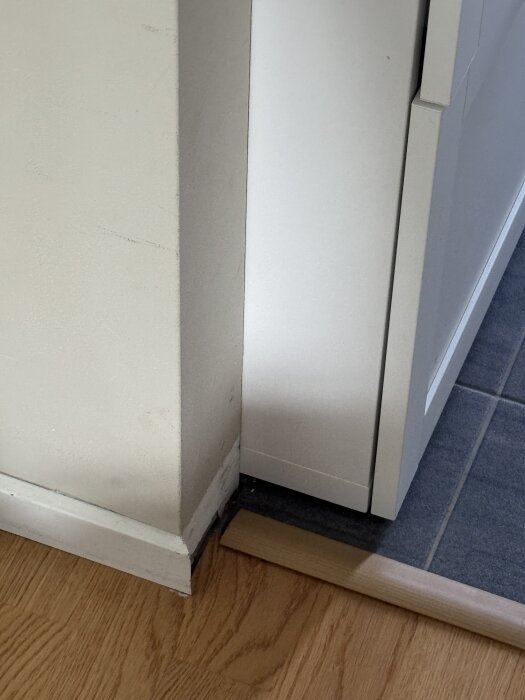 Vägg med behov av förlängning för att hallmöbel ska se inbyggd ut, trä- och klinkergolv synliga.