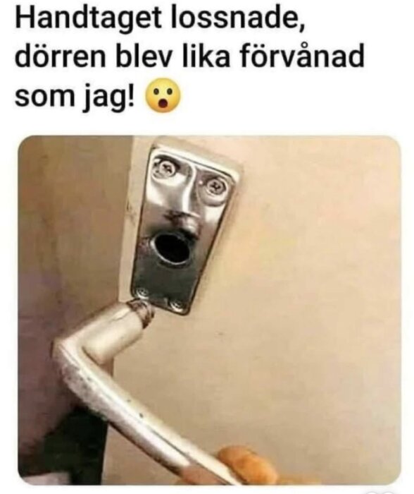 Dörrhandtag lossnat från dörren, kvar finns ett ansiktsliknande intryck med två skruvögon och ett hål för mun, som ser förvånat ut.