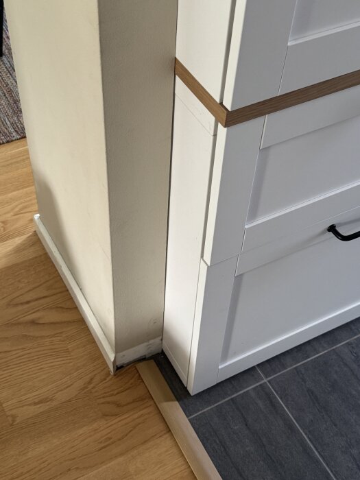 Vägg och hallmöbel med en kant där golv möts; diskussion om att förlänga väggen för att skapa en inbyggd känsla för möbeln.