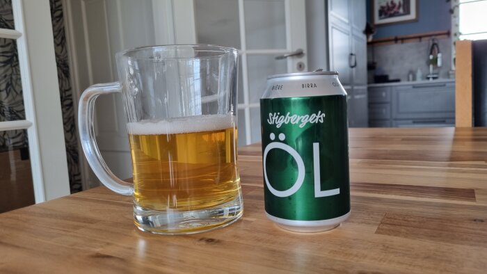 Ett glas öl och en burk Stigbergets öl på ett köksbord.