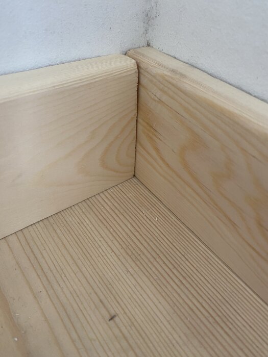 Hörnsammanfogning av träplankor vid väggen, diskussion om snyggare utförande och efterlikna originallistens detaljrika udd.