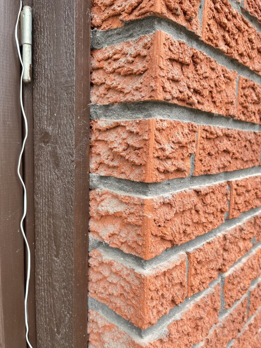 Röd tegelvägg med texturerat mönster vid dörrkarm, kanske från ett hus byggt 1974 i Sörmland.