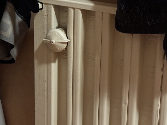 Vitt vattenelement med ventil, potentiell avstängare bakom mutter. Fråga kring koppling till bergvärmepump vid renovering av toalett.