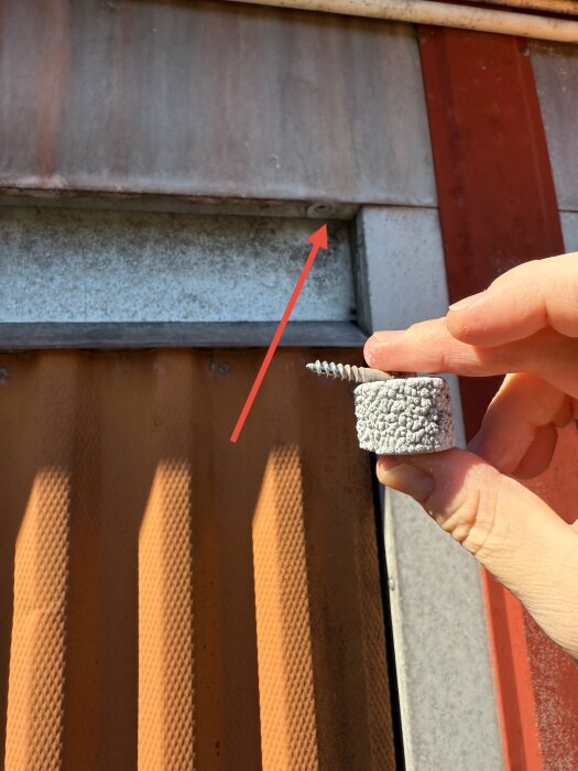 Gammal garageport med liten grå dämpare eller stoppare i handen, indikerad med pil, används för att ta emot porten vid öppning.