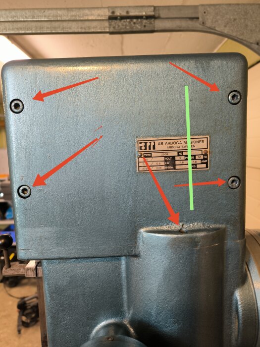 Närbild av växelhuset på U2850 med fem lossade skruvar markerade med röda pilar; ett grönt streck visar del som verkar sitta fast.