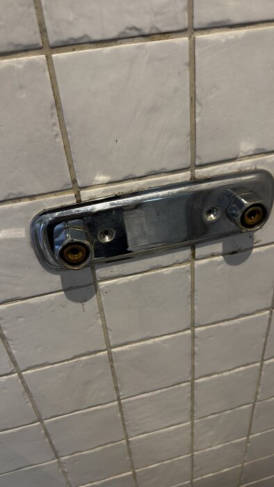 Gammalt blandarfäste med kopparfärgade rör på kaklad vägg, osäker på hur det ska lossas utan att skada kakelplattorna.