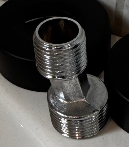 Adapternippel i metall med gängor, troligen använd för anslutning mellan blandarfäste och blandare.