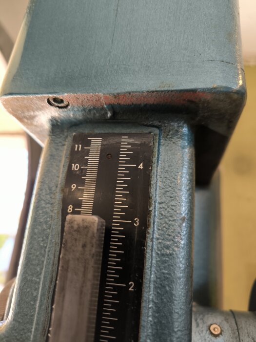 Närbild av en vertikal skala på en blå maskinkomponent, markerad mellan 0 och 11.