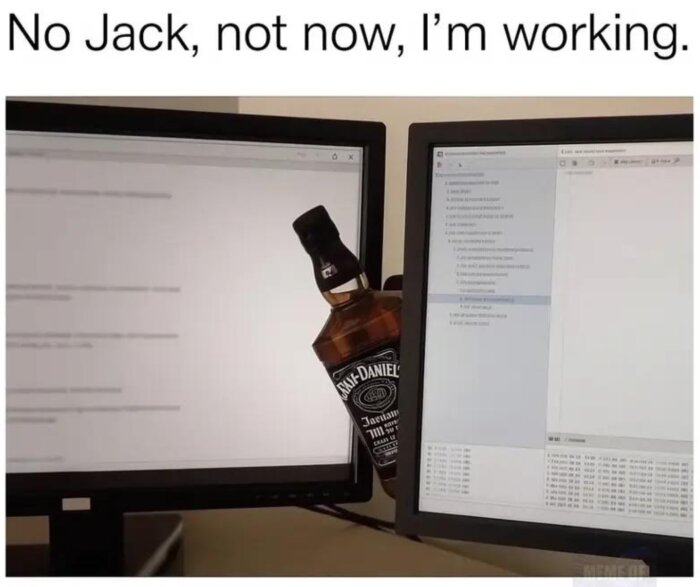 En flaska whisky kilar in sig mellan två datorskärmar med texten "No Jack, not now, I'm working" ovanför.