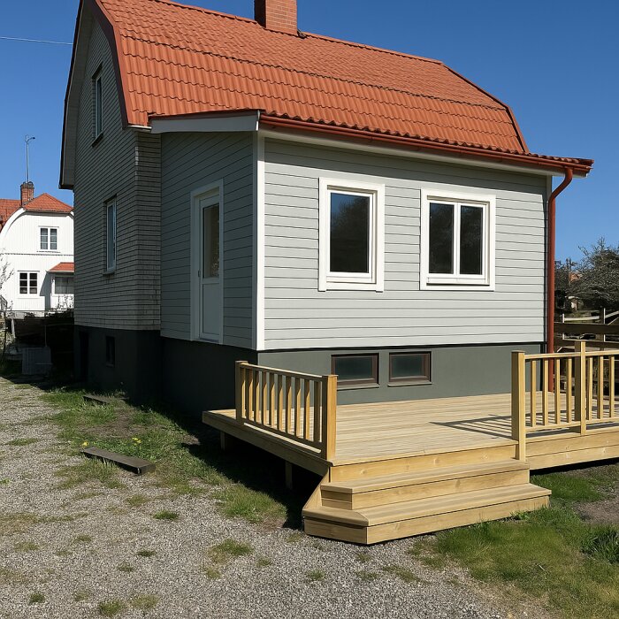 Altan av trä på baksidan av ett hus med grå fasad och rött tak, förslag på plats för nytt sovrum ovanför källargarage.