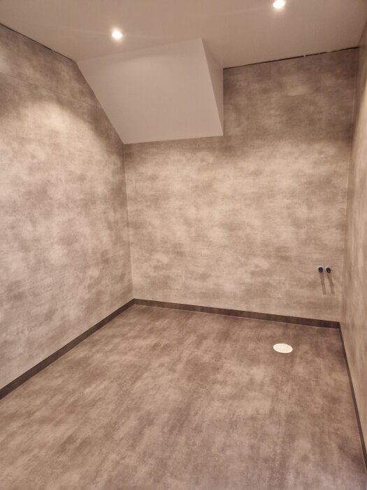 Renoverad förrådsyta med grått LVT-golv och diskreta väggar, tak och belysning. Rummet är redo för koppling av vatten och installationer.