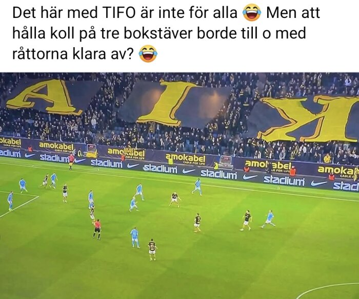 En fotbollsmatch med åskådare som håller upp stora bokstäverna "AIK" på läktaren.