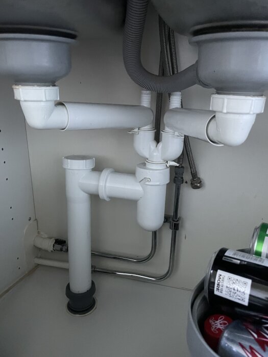 Under diskbänkens rörsystem med avloppsanslutningar och rör för vatten, synliga kopplingar för eventuell anslutning av diskmaskin.