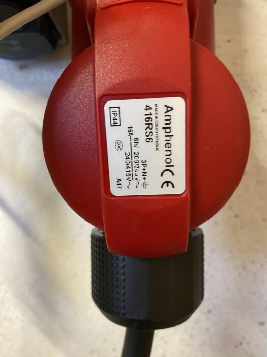 Rött 3-fasuttag med etikett från Amphenol, märkt 16A 6h 200/220V 240/415V, beskriver en installationsfråga om jordfelsbrytare.