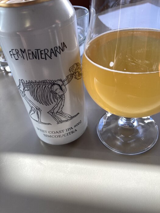 En burk Fermenterarna West Coast IPA Simcoe/Citra bredvid ett glas med gyllene öl.