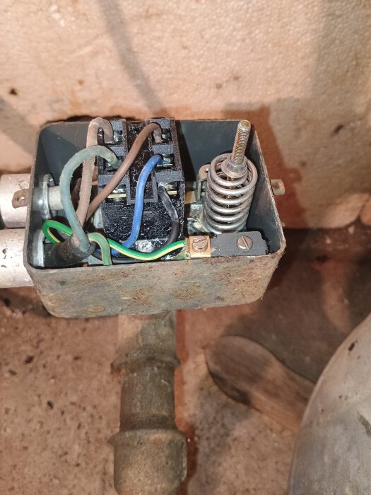 Trasig tryckvakt med exponerade kablar och rost i äldre stuga.